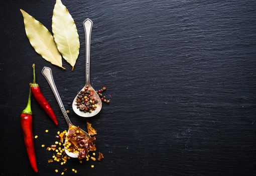 Spices withdifferent types of pepper on dark background with copyspace