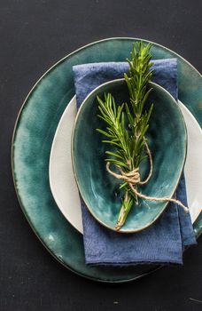 Table setting with fresh rosemary and rustic silverware on dark wooden table
