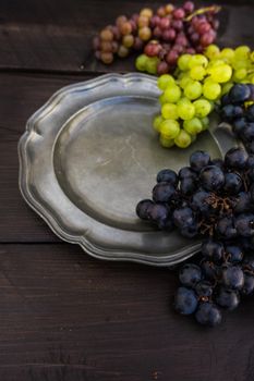 Fresh organic autumnal grapes on rustic plates on old wooden table with copyspace