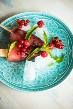 Summer fruit dessert - strawberry lollipops with mint and ice on rustic plate on concrete background