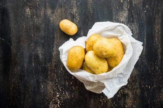 Organic potatoes on vintage pan on dark wooden table with copyspace