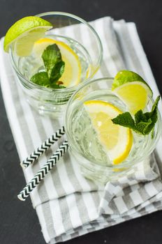 Fresh homemade detox lemonade with lime, lemon, rosemary, mint and ice on rustic wooden table with copyspace