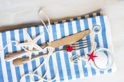Summer vacation marine table setting with rustic plates and silverware on wooden background with copyspace