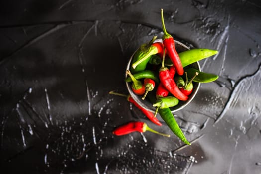 Organic chilli peppers on a pan on dark wooden background with copyspace