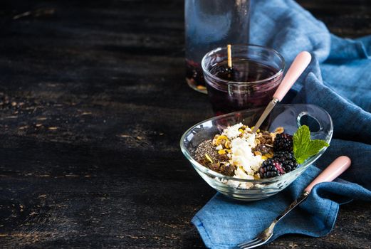 Oatmeal with chia and blackberries as a organic breakfast concept and detox drink of blackberries and lemon on dark rustic table