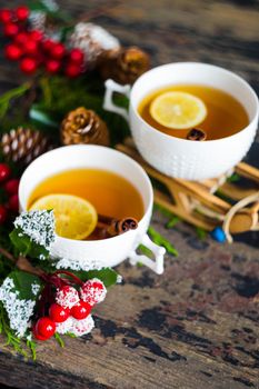 Cup of tea with lemon and cinnamon spice and Christmas decoration on rustic wooden table