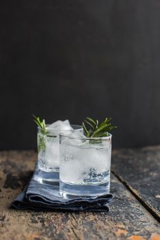 Fresh homemade lemonade with lime, lemon, rosemary and ice on rustic wooden table with copyspace