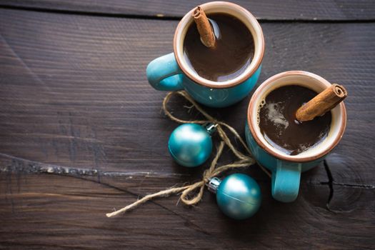 Mug of coffee with spices - cinnamon sticks and anise star with Christmas decor on dark wooden table with copyspace