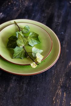 Rustic table setting with wild grape leaves on the plate on dark wooden table