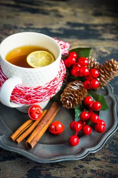 Cup of tea with lemon and cinnamon spice and Christmas decoration on rustic wooden table