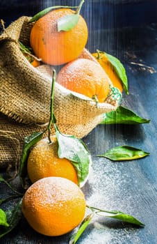 Ripe organic oranges in bag on dark rustic wooden table