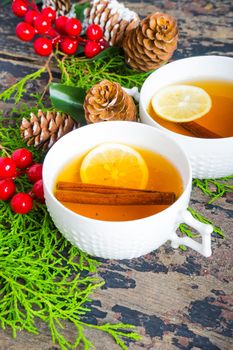 Cup of tea with lemon and cinnamon spice and Christmas decoration on rustic wooden table