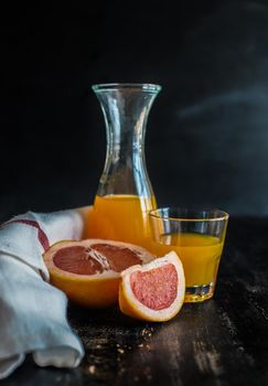 Organic fresh grapefruit juice in vintage bottle with ruits on dark wooden table