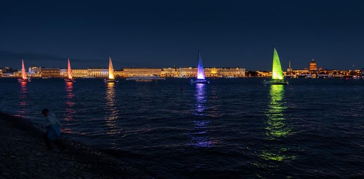 Russia, St. Petersburg, 07 August 2022: A few sailboats with sails illuminated in the tricolor of Russia go in the city center at the celebration of the opening of the sailing week, sightseeing . High quality photo