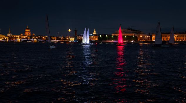 Russia, St. Petersburg, 07 August 2022: A few sailboats with sails illuminated in the tricolor of Russia go in the city center at the celebration of the opening of the sailing week, sightseeing . High quality photo