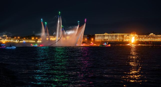 A lot of flyboarders and brightly dressed up jet skiers perform their show at a holiday in the center of St. Petersburg at night, water activities. High quality photo