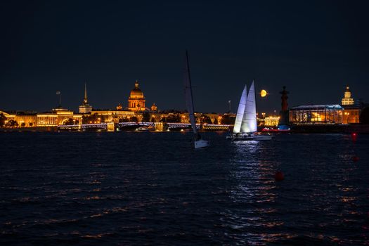 Russia, St. Petersburg, 07 August 2022: A few sailboats with sails illuminated in the tricolor of Russia go in the city center at the celebration of the opening of the sailing week, sightseeing . High quality photo