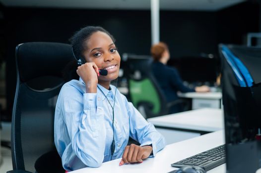 African young woman talking to a client on a headset. Female employee of the call center