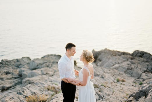 Bride and groom look into each other eyes, hugging forearms. High quality photo