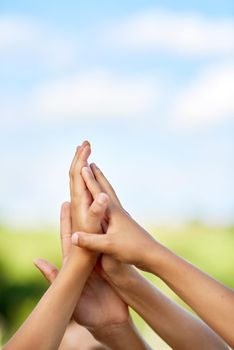 This one is for the kids. a group of children giving each other a high five outdoors