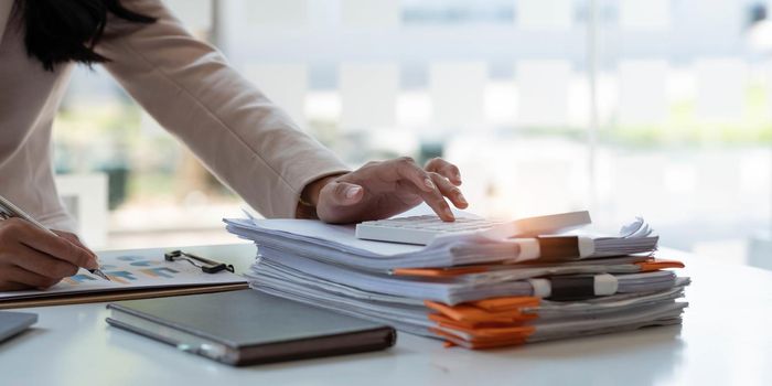 Close up Businessman using calculator and laptop for calaulating finance, tax, accounting, statistics and analytic research concept.