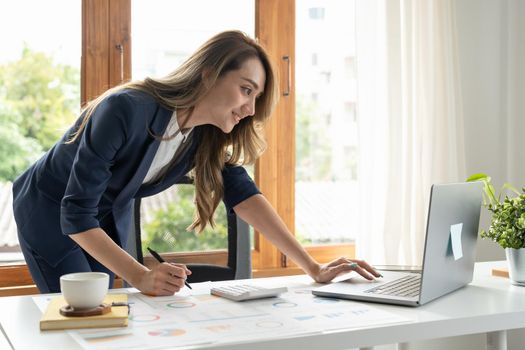 Business woman using calculator and laptop for do math finance on wooden desk in office and business working background, tax, accounting, statistics and analytic research concept.