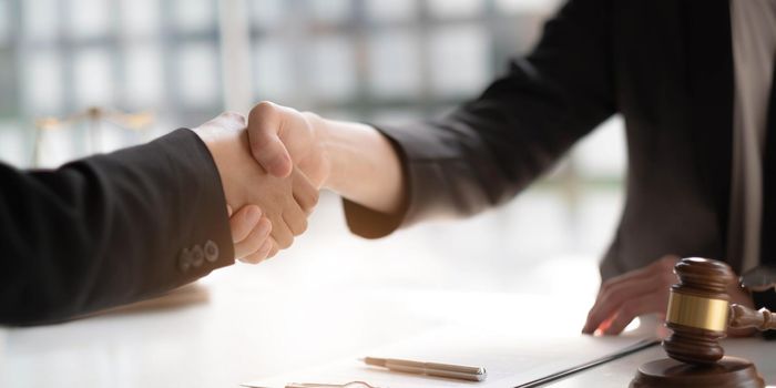 Businessman shaking hands partner lawyers or attorneys discussing a contract agreement..