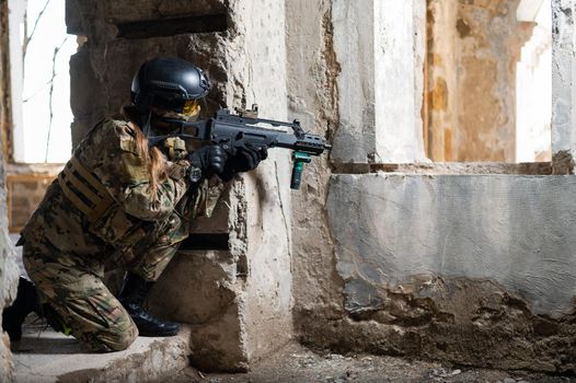 A woman in an army uniform shoots a firearm in an abandoned building