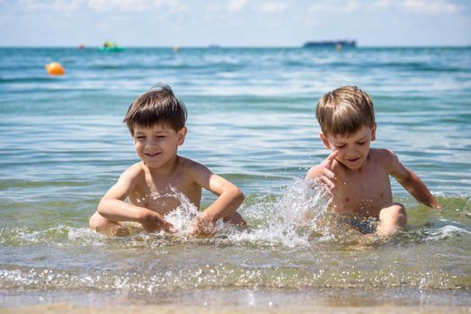 Happy family playing in blue water of swimming pool on a tropical resort at the sea. Summer vacations concept. Two brother kids are best friends.