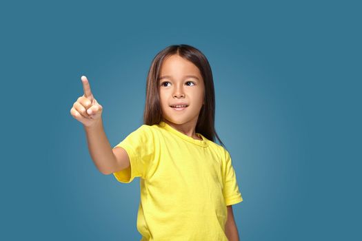 Cute girl shows her finger on blue background