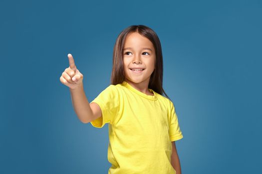 Cute girl shows her finger on blue background