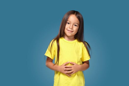 Little girl in yellow t-shirt is smiling on blue background