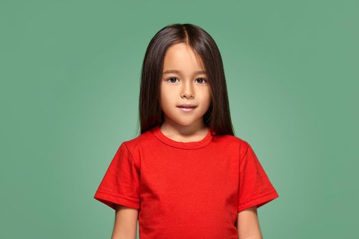 Little girl in red t-shirt is smiling in red t-shirt green background