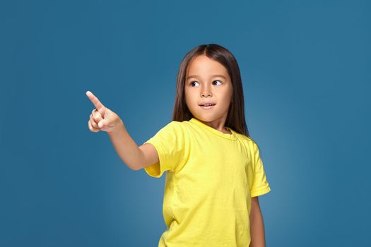 Cute girl shows her finger on blue background