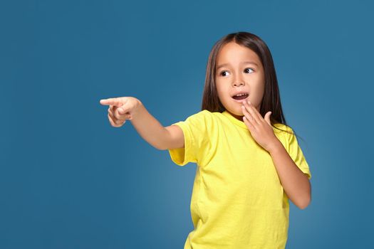 Cute girl shows her finger on blue background