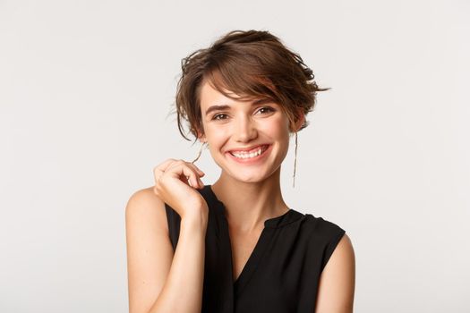 Close-up of elegant businesswoman smiling at camera satisfied, standing over white background.