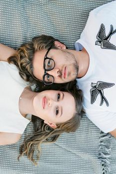 Man and woman lie head to head on a blanket. Top view. High quality photo