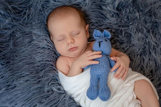 Newborn baby boy in bed. New born child sleeping under a white knitted blanket. Children sleep. Bedding for kids. Infant napping in bed. Healthy little kid shortly after birth. Cable knit textile.