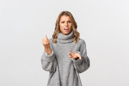 Portrait of confused girlfriend showing finger without wedding ring and looking puzzled, standing over white background.