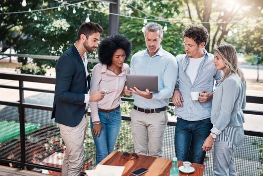 Moving their meeting outdoors for a change. a group of businesspeople working together on a laptop outdoors