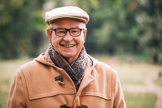 Outdoor portrait of cheerful senior man in winter coat.