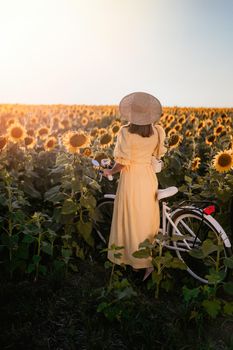 Attractive woman in timeless dress with retro styled bicycle in sunflowers field. Vintage fashion, amazing adventure, countryside activity, healthy lifestyle. High quality photo