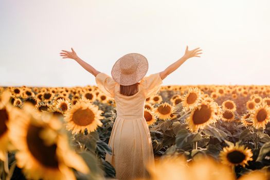 Woman with open arms in sunflowers field. Yellow colors, warm toning. Free girl in straw hat and retro dress. Vintage timeless fashion, amazing adventure, countryside, freedom scene.High quality photo