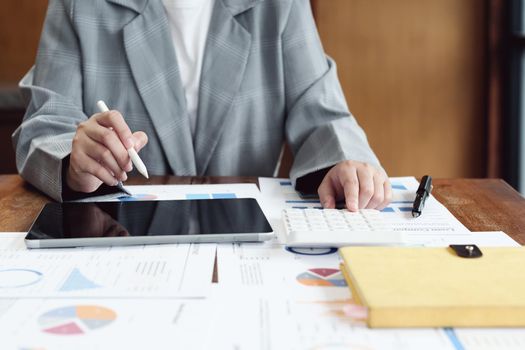 Business woman using calculator, tablet and documents to work.