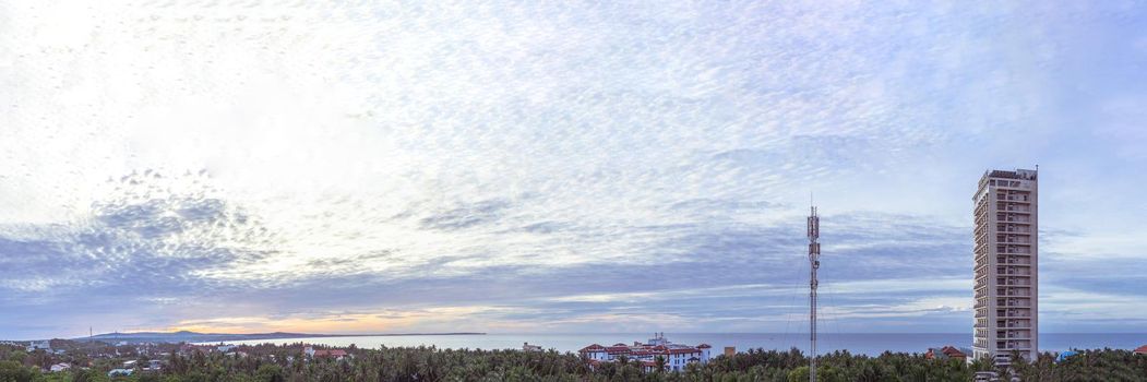 Long panorama banner. Light soft blue orange sunrise reflections dramatic sky cumulus clouds. Early rising in the city. High skyscraper multi-storey building, antenna. Morning calm time.