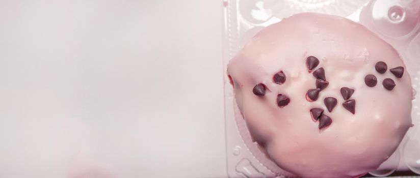 Delicious doughnut with icing sugar and chocolate chips top view, banner with a copy of the space on the left, pink tinting.