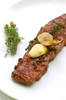 Close up of an appetizing beef steak, garlic and thyme on a plate