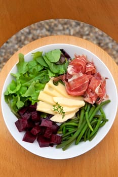 Ham, cheese, beet and beans in a mixed salad