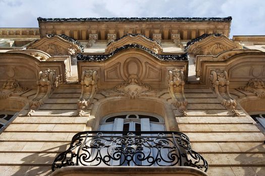 Windows and sculptures on the stoned facade of a French mansion in Bordeaux