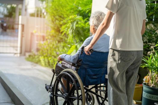 Caregiver help and care Asian senior or elderly old lady woman patient sitting on wheelchair to ramp in nursing hospital, healthy strong medical concept.